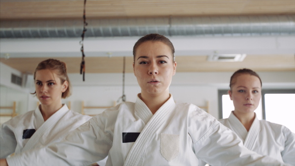 A group of young women practising karate indoors in gym.