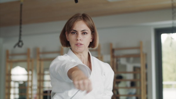 Front view of young woman practising karate indoors in gym.