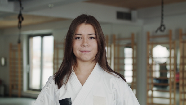 A portrait of young karate woman standing indoors in gym, looking at camera.