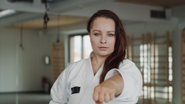 Front view of young woman practising karate indoors in gym.