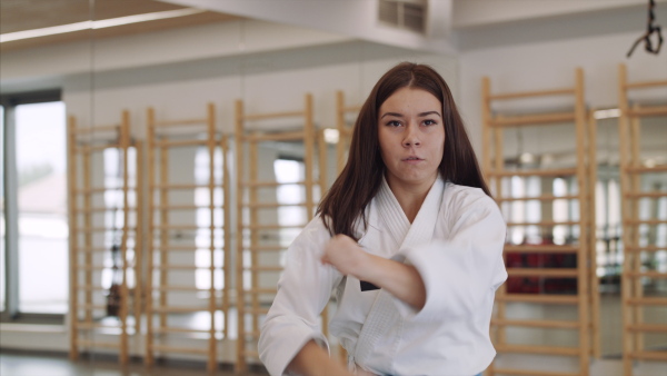 Front view of young woman practising karate indoors in gym.