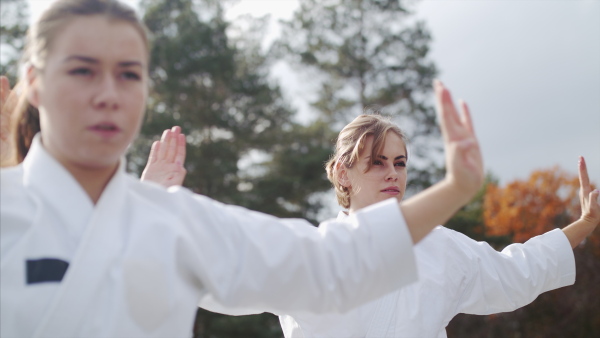 Two young women practising karate outdoors on terrace.