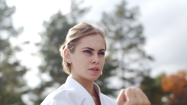 An attractive young woman practising karate outdoors on terrace.