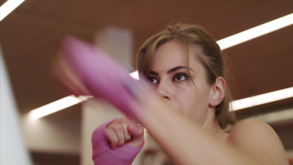 Concentrated young woman doing exercise indoors in gym, boxing.