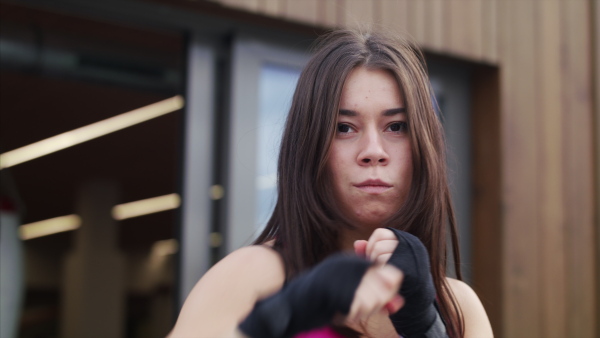 A front view of young woman practising karate outdoors on terrace.