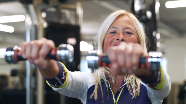 Happy senior woman with dumbbells in gym, doing exercise.