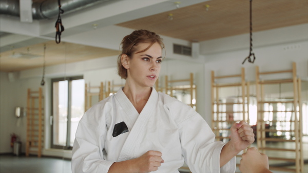 Two young women practising karate indoors in gym.