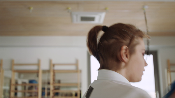 Two young women practising karate indoors in gym.