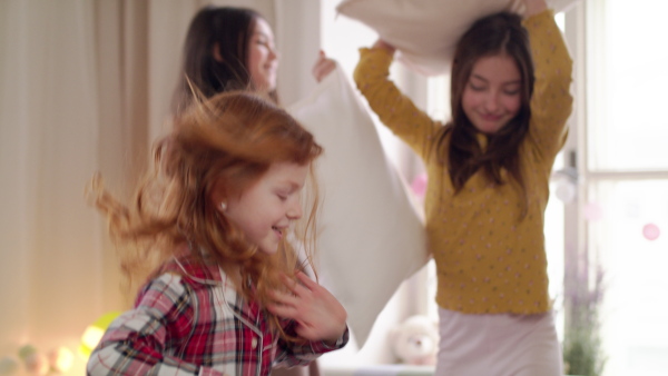 A group of small girls friends jumping on bed on slumber party. Slow motion.