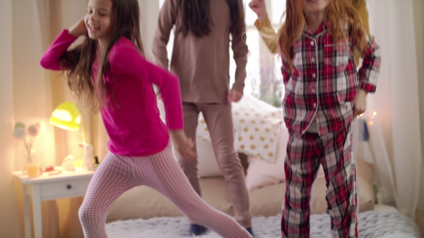 A group of small girls friends jumping on bed on slumber party. Slow motion.