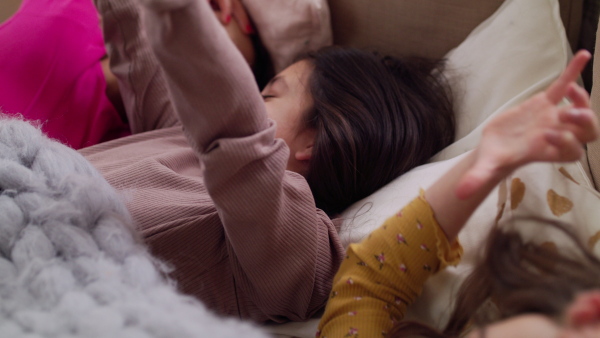 Close-up of group of small girls friends waking up in bed in the morning, slumber party concept.