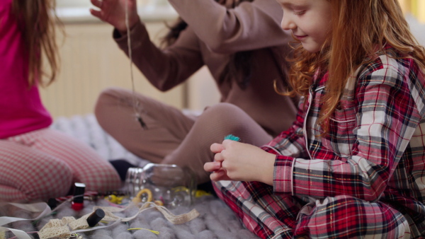 Group of small girls friends in pajamas playing on bed on slumber party.