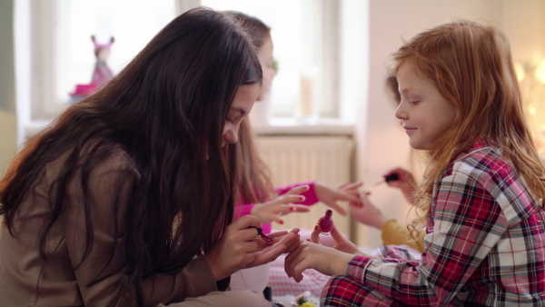 Group of small girls friends painting nails on slumber party, midsection.