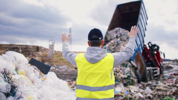 A rear view of worker on landfill, waste management and environmental concept.