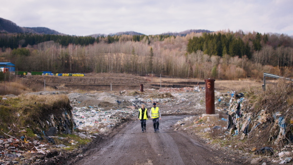 Man and woman workers walking on landfill, waste management and environmental concept.