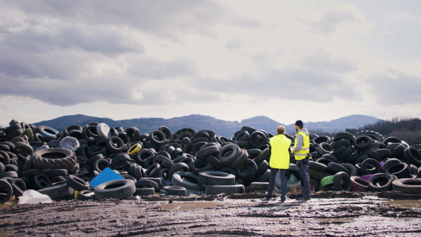 Rear view of man and woman workers on landfill, waste management and environmental concept. Copy space.