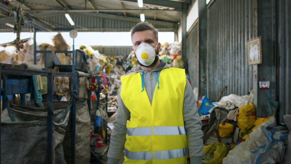 Front view of worker with face mask on landfill, waste management and environmental concept.