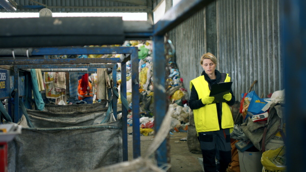 Front view of woman worker walking on landfill, waste management concept.