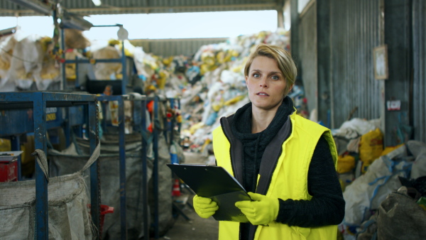 Front view of woman worker standing on landfill, waste management concept.