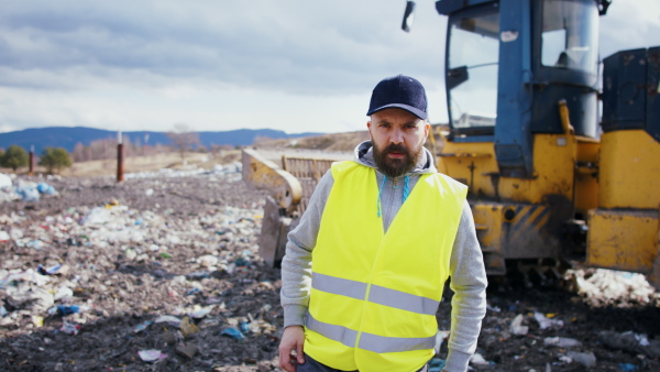 Front view of worker looking at camera on landfill, waste management and environmental concept.