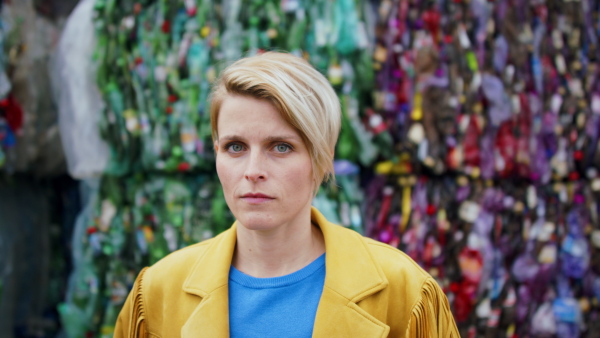 Front view portrait of woman standing and looking at camera on landfill, waste management and environmental concept.