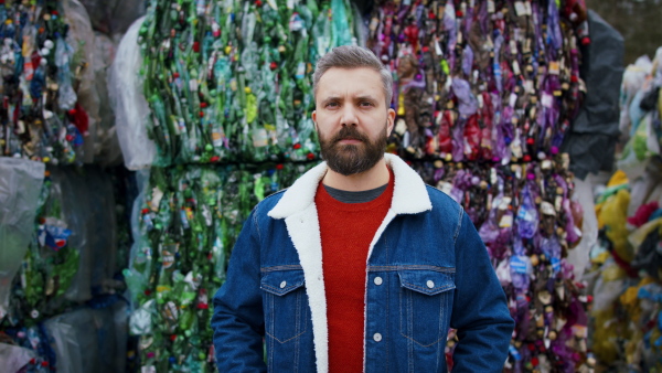 Front view portrait of man standing and looking at camera on landfill, waste management and environmental concept.