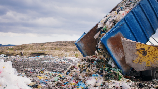 Dump truck unloading waste on landfill, an environmental concept.