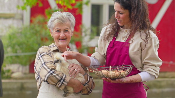 A pair of farmers holding a chicken and looking at camera. Community farming concept.