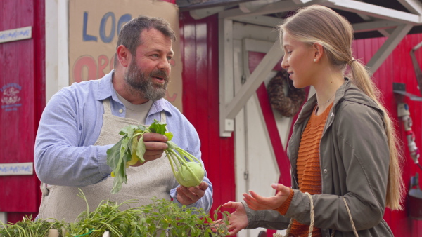 A young woman buying fresh vegetables on farm market. Community farming concept.