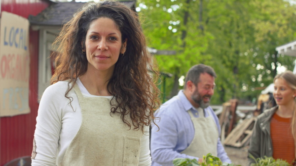 A woman farmer standing in front of farm market, looking at camera. Community farming concept.