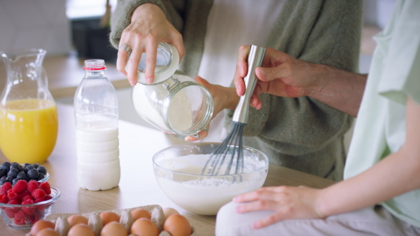 A beautiful family at home preparing a pancake mix together.