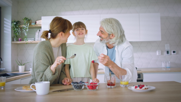 A beautiful family at home having a breakfast together, looking at camera.