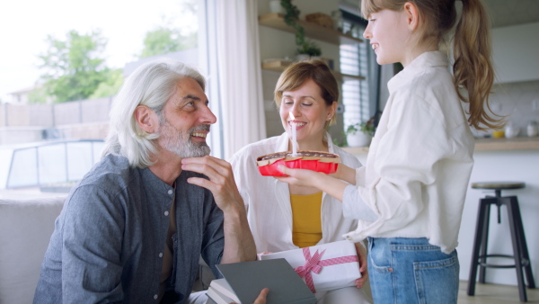 A beautiful family celebrating fathers birthday, daughter giving him a cake.