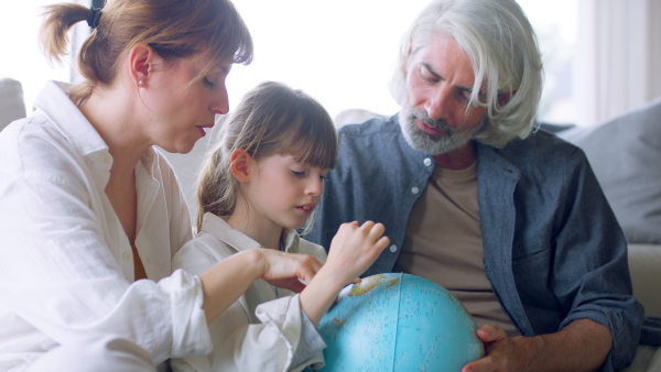 A beautiful family at home, sitting on sofa, having with globe.