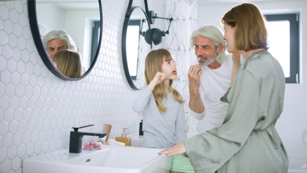 Happy family tooth brushing teeth together in the morning, getting ready for day.