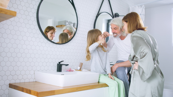 Happy family tooth brushing teeth together in the morning, getting ready for day.