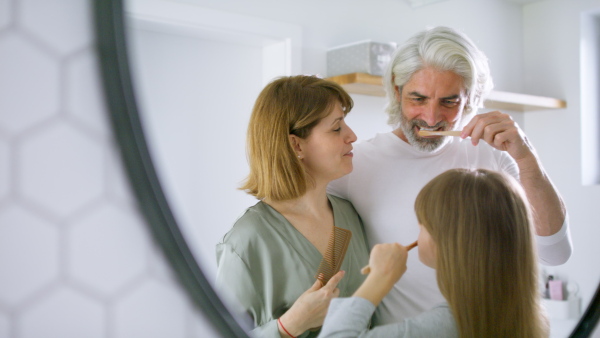 Happy family tooth brushing teeth together in the morning, getting ready for day.