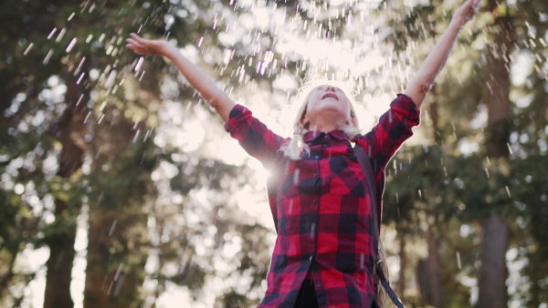 An active senior woman hiker standing outdoors in nature, resting. Slow motion.