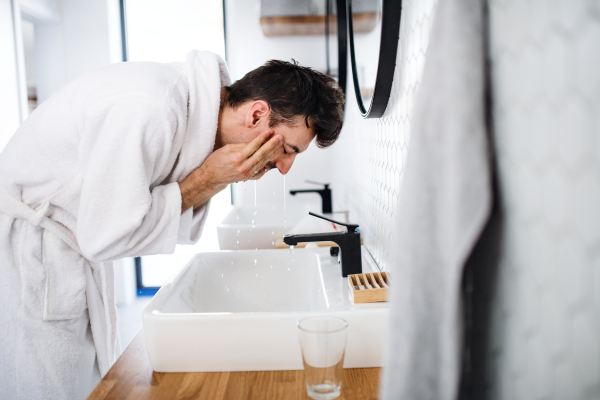 Young man washing face in the bathroom in the morning, a daily routine.