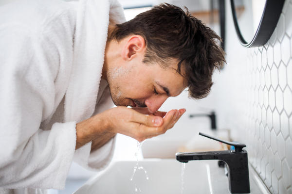 Young man washing face in the bathroom in the morning, a daily routine.