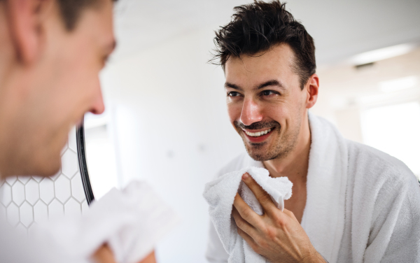 Young man washing face in the bathroom in the morning, a daily routine.