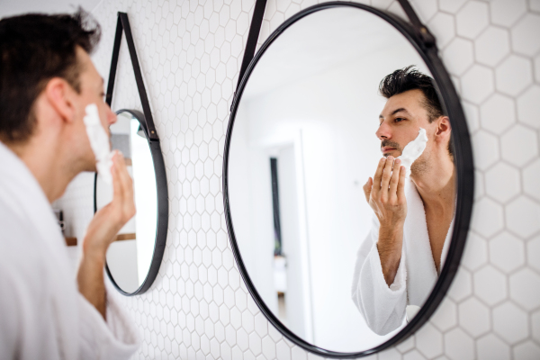 A young man shaving in the bathroom in the morning, a daily routine.