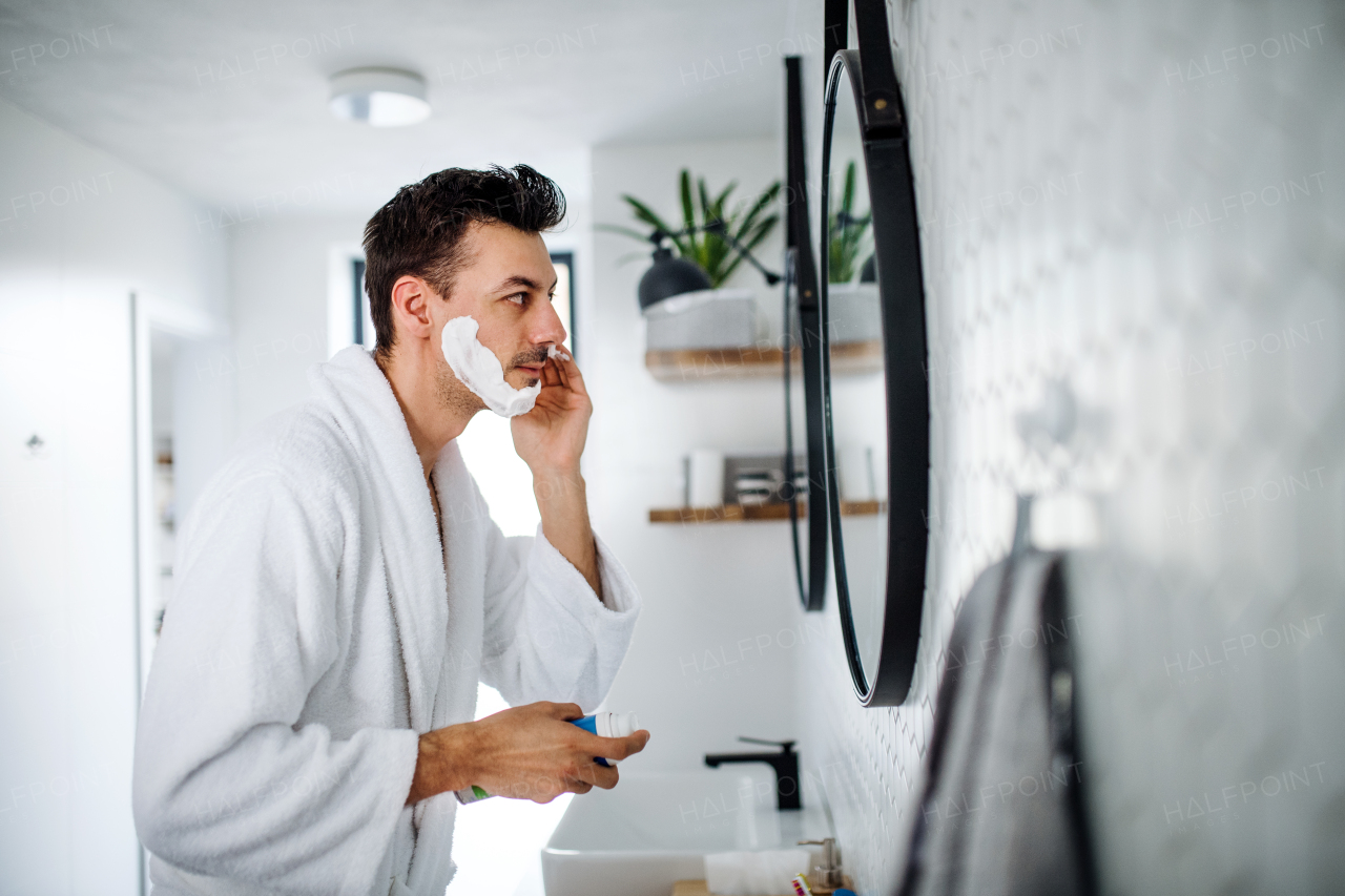 A young man shaving in the bathroom in the morning, a daily routine.