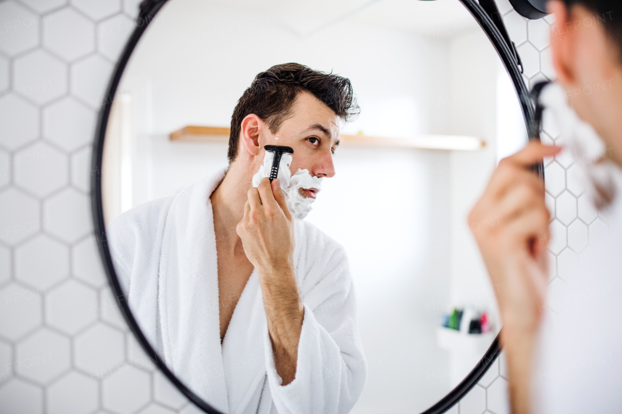 A young man shaving in the bathroom in the morning, a daily routine.