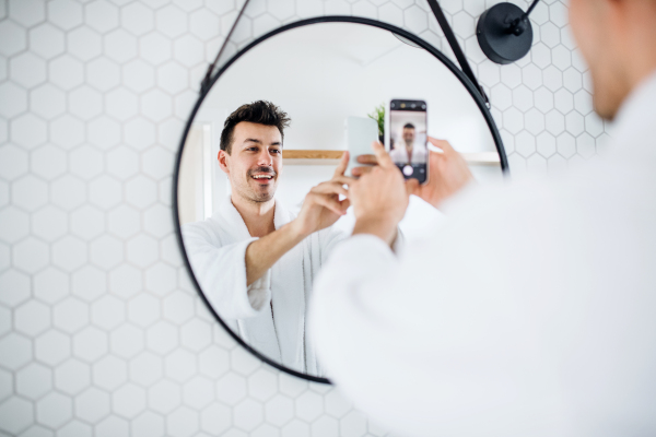 Young man in the bathroom in the morning, taking selfie. A daily routine.