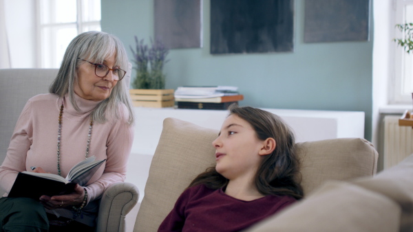 Sad and depressed small girl talking to psychotherapist indoors, mental health concept.