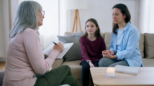 Sad and depressed small girl and mother talking to therapist indoors, mental health concept.