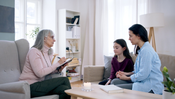 Sad and depressed small girl and mother talking to therapist indoors, mental health concept.