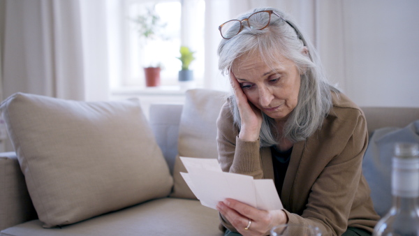 Front view of depressed woman looking at photographs indoors, mental health concept.