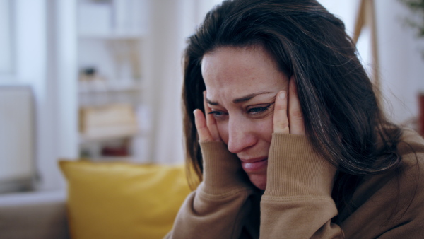 Close-up of crying sad and depressed woman indoors, mental health concept.